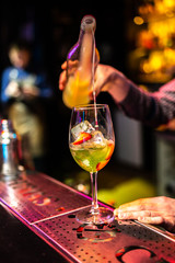 Expert bartender making green cocktail with kiwi, strawberry and lime on the bar, blurred background.
