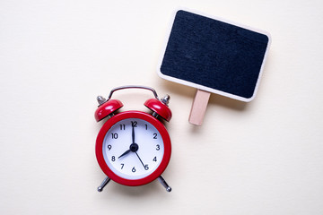 Blank vintage small chalkboard for text on purple background and a red alarm clock. . Minimal concept