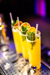 Close-up cocktail with mint and dried orange on the bar, blurred background.