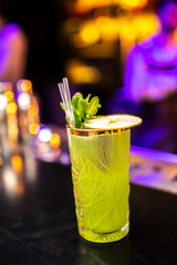 Close-up cocktail with mint and dried apple on the bar, blurred background.