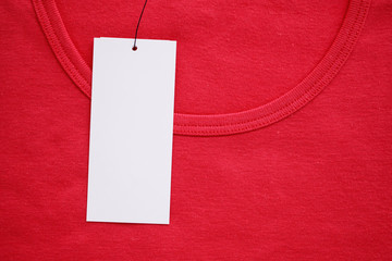 Blank white clothes tag label on new red shirt