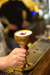 Close up hand with cocktail in gold mental cup