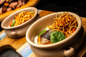 Grilled fish fiillet steak with fries and spinach leaves in deep plate