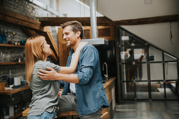 Cute young couple hugging while cooking in their kitchen