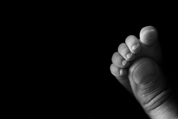 Little foot of a newborn baby on a black background close-up