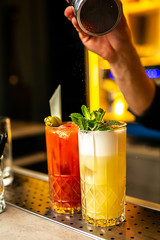 Close-up three cocktails with dried lime and mint on the bar, blood marry blurred background.