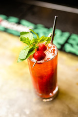 Lemonade cocktail with strawberry and mint on the bar, blurred background.