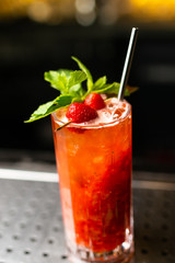 Lemonade cocktail with strawberry and mint on the bar, blurred background.