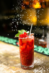 Lemonade cocktail with strawberry and mint on the bar, blurred background.