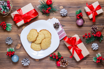 Christmas, New Year background. Flat-lay postcards, sparkling toys, cookies, pine cone over a wooden table, top view.
