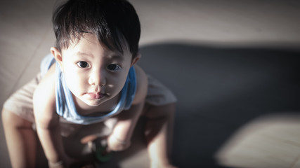 Close up portrait of a little Asian boy sitting and look up.