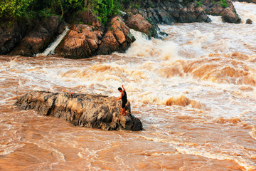 Laotian fisherman casting fishing net on the Mekong River.
