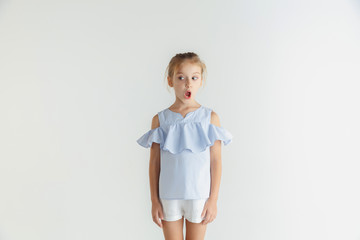 Stylish little smiling girl posing in casual clothes isolated on white background. Caucasian blonde female model. Human emotions, facial expression, childhood. Shocked, thoughtful, looking at side.