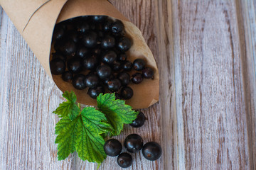 Currant. Ripe black currant in a paper bag on an old wooden surface.