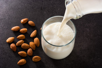 Pouring almond milk in glass on black background