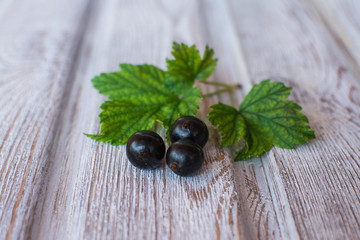Currant. A sprig of ripe black currant on an old wooden surface. Close-up.