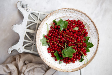 Fresh red currant berries in a old bowl on marble background with copy space