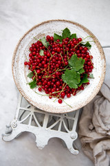 Fresh red currant berries in a old bowl on marble background with copy space