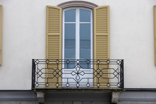 balcone in ferro battuto con persiane color senape 