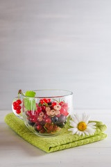 fresh multicolored currant berries in a mug on a white background