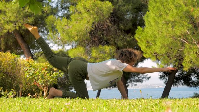 Caucasian lady doing yoga on front yard. Morning exercises on fresh air. Woman cares about her body. Female strengthening body by doing exercises fitness yoga