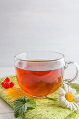 tea in a mug with berries and chamomile on a white background