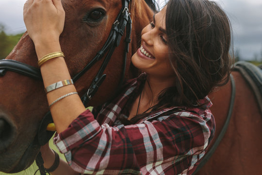 Smiling woman petting her horse
