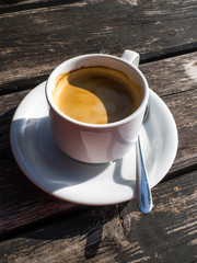 cup of coffe, image shape from shadow Yin Yang, on wooden background. White ceramic cup, stylish toning, copy space