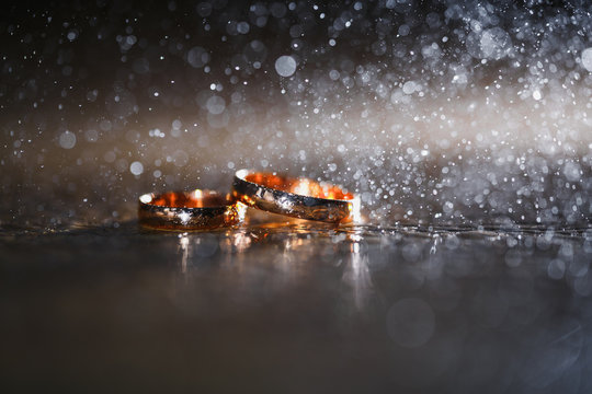 gold wedding rings. creative. splashes of water. bokeh