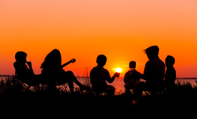 Fototapeta na wymiar Silhouette of people sitting on the beach with campfire at sunse