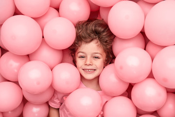 Fototapeta na wymiar Cheerful kid playing in pink balloons