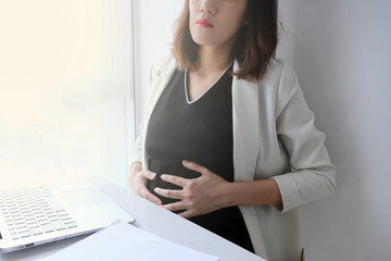 young asian pregnant  working in the office or home with paperwork calculator laptop and computer. financial accounting concept.