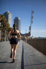 Beautiful woman in sport clothes running on the seafront in Barcelona (SPAIN)