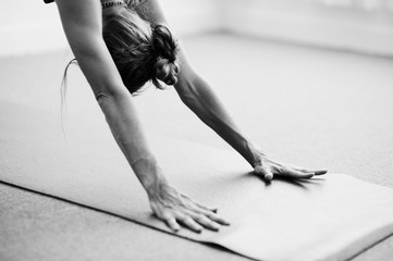 Photographie d& 39 art classique en noir et blanc d& 39 une femme pratiquant une pose de yoga avancée à l& 39 intérieur sur un tapis de yoga. Bras dynamiques de la femme en Downward Dog.