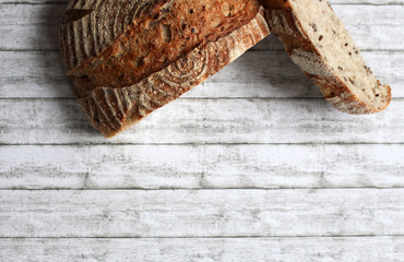 crusty vintage bread with one cut loaf on light wooden background with copy space