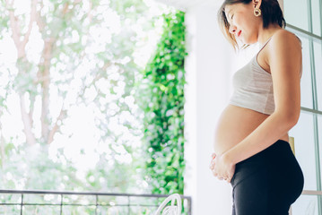 Fototapeta na wymiar 24 Weeks pregnant woman relaxing near window at home in bedroom