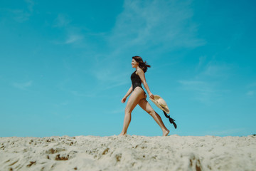 woman at sand beach in black swimsuit blue sky on background