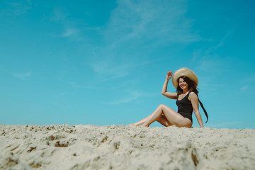 Fototapeta na wymiar woman at sand beach in black swimsuit blue sky on background
