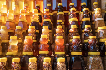 Many jars with fresh organic honey on farm market. Colorful honey with fruit berries and nuts in the jar, on a market in Altai.