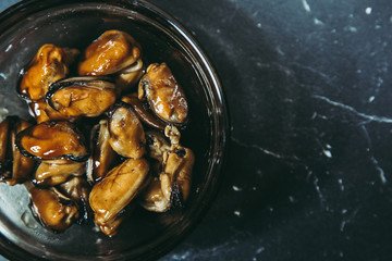 Fried hot appetizing mussels in soy sauce in a bowl Dark background