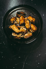 Fried hot appetizing mussels in soy sauce in a bowl Dark background