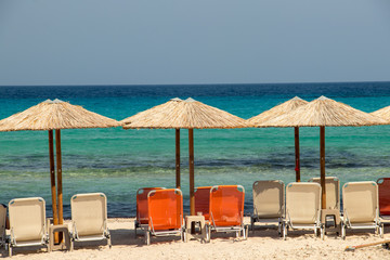 Umbrellas with chairs on beach in Milos