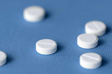 White tablets scattered on a blue background close up