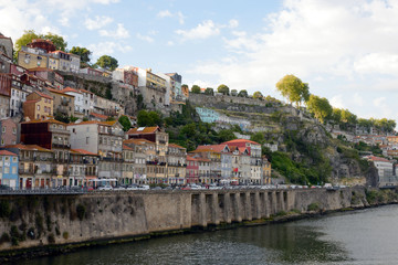 Fototapeta na wymiar Beautiful view of the city of Porto, Portugal from the river Duoro. Roofs of houses, mountains and the promenade in the light of the setting sun.