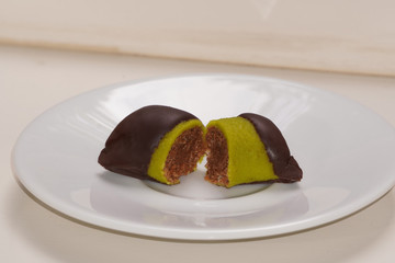 candy, pistachio in chocolate lying on white plate, healthy sweets