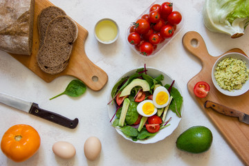 Vegetarian meal prep with eggs, avocado, salad and tomato.Top view.