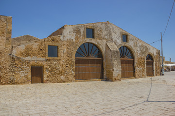 Marzamemi in Sicily, wide front view of the facade of an historical tonnara, a traditional tuna factory, in yellow stones