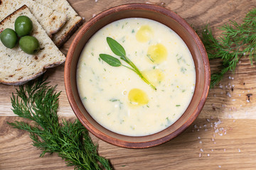 Fresh hot homemade cream soup with vegetables, cheese, olive oil, fresh sage leaves and spices. French onion soup. Healthy food concept.