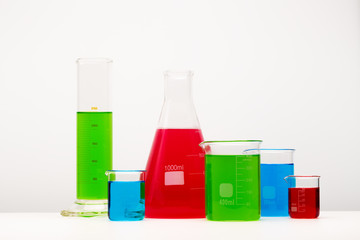Laboratory glassware with liquids of different colors  on table.
