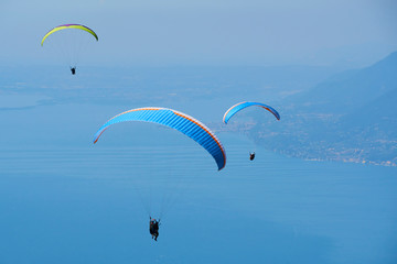 Paraglider flying over the Garda Lake (Lago di Garda or Lago Benaco). Paragliding on Monte Baldo. Panorama of the gorgeous Garda lake surrounded by mountains, Malcesine, Italy